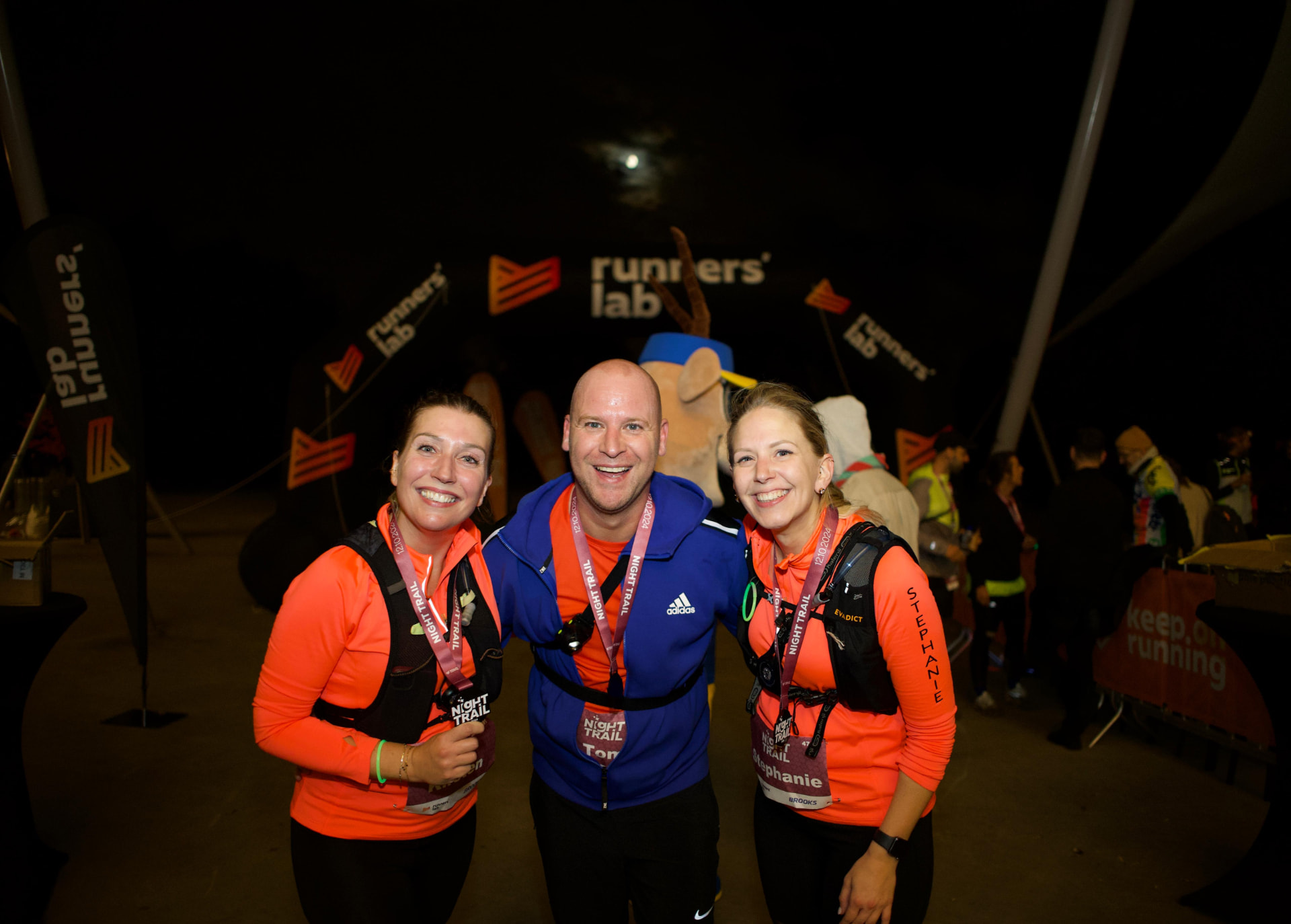 Three Night Trail runners smiling together at the finish area